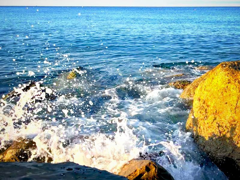 Фото: Лигурийское море на восходе солнца, пена морских волн на камнях